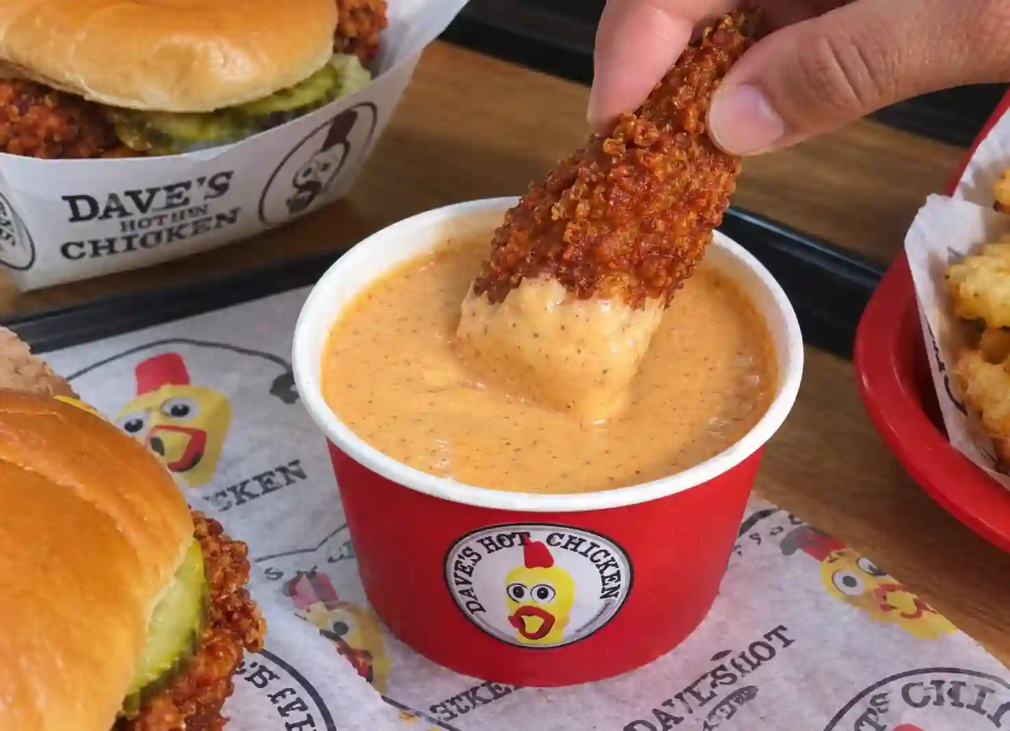 Dave’s Hot Chicken tender dipped in creamy hot chicken sauce