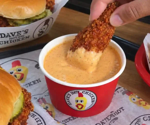 Dave’s Hot Chicken tender dipped in creamy hot chicken sauce